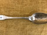 une cuillère ancienne en argent portant le chiffre 26, posée sur une table