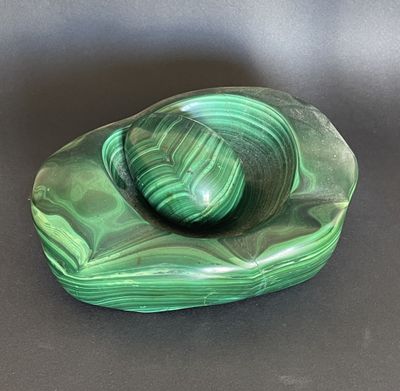 bol en marbre vert posé sur une surface noire, avec un fond noir