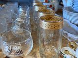 many glasses and cups sitting on a wooden table