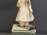 an old doll is standing on top of a piece of luggage