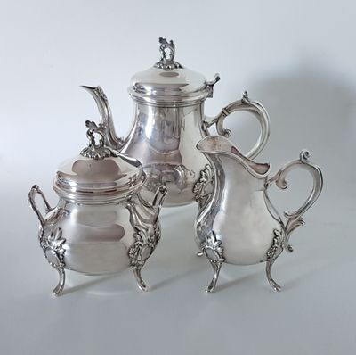 three silver teapots and a coffee pot sitting on a table
