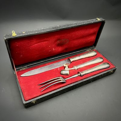 un service d'argenterie dans un coffret rouge posé sur une table