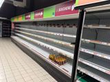 de nombreuses étagères vides dans un magasin, sur lesquelles sont posées des boissons