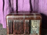 an old radio sitting on the floor next to a purple curtain