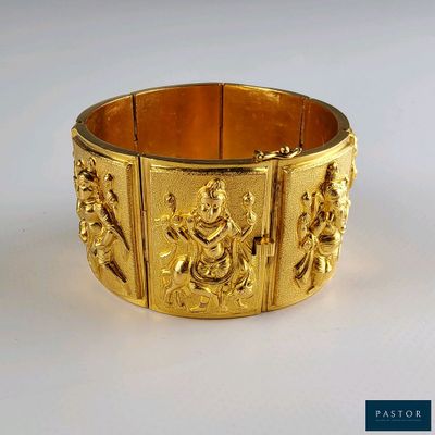 gros plan d'un bracelet en or sur une surface blanche