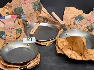 several pots and pans are sitting on a table with a price tag