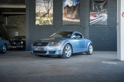 une voiture bleue garée dans un garage avec d'autres voitures