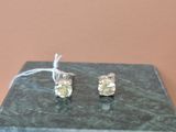 une paire de boucles d'oreilles à clous ornées de diamants jaunes, posées sur un bloc de marbre