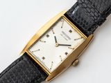 a gold watch with a black strap on a white surface