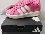 Des baskets Adidas roses et blanches sont posées sur une boîte