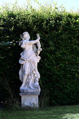 a statue of a woman holding a bird in a garden