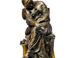 une vieille statue en bronze représentant un homme assis sur un banc
