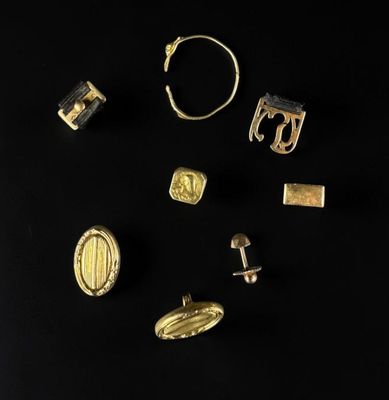 plusieurs bijoux en or et en argent posés sur un fond noir