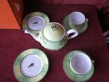 quatre tasses et soucoupes posées sur une table, à côté d'une boîte