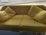 a yellow couch with two pillows on it in a living room