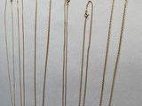 Plusieurs colliers en or sont disposés en rangée sur une surface blanche