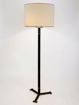 the lamp is on a black stand with a white shade on it