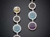 a pair of earrings with multi colored stones on a black surface