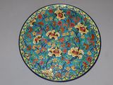 une assiette bleue et jaune décorée de fleurs et de feuilles