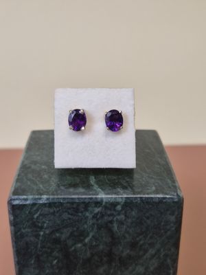 une paire de boucles d'oreilles en amethorate posées sur un bloc de marbre