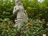 une statue au milieu d'un jardin, entourée de buissons