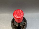 a bottle with a red lid sitting on a metal surface