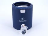 a small glass penguin sitting in front of a blue container