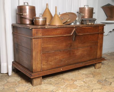 un coffre en bois sur lequel sont posées des casseroles et des poêles