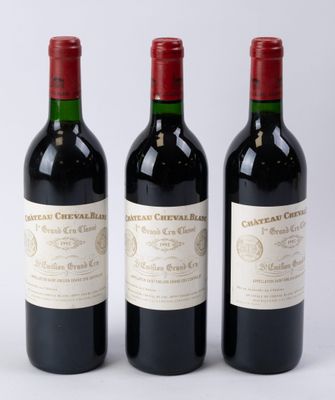 trois bouteilles de vin rouge posées l'une à côté de l'autre sur une surface blanche