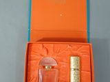 une boîte orange contenant un flacon de parfum et un briquet