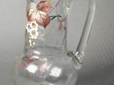 a clear glass pitcher with a floral design on it