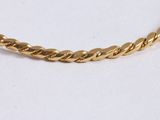 a close up of a gold rope bracelet on a white surface