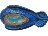 a blue fish shaped container with a stone in it