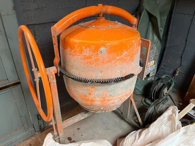 an orange cement mixer sitting in the corner of a room