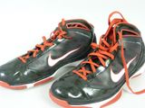 une paire de chaussures noires et orange avec des lacets orange sur fond blanc