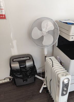 une photo d'une pièce avec un ventilateur, une imprimante et son boîtier
