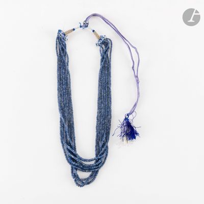 un gros plan d'un collier posé sur une surface blanche, avec un cordon violet