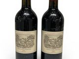 two bottles of red wine sitting next to each other on a white surface