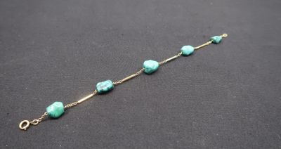 a close up of a bracelet with turquoise beads on a black surface