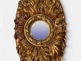 un miroir doré accroché au mur, à côté d'un mur blanc