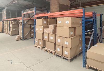 Les cartons sont empilés sur des palettes dans un grand entrepôt équipé de nombreuses étagères.