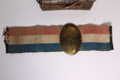 une ceinture avec une boucle dorée et une ceinture marron avec une bande bleue, blanche et rouge