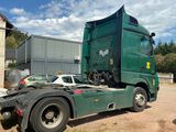 a green semi truck that is parked in the dirt