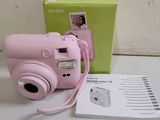 a pink camera sitting on a table next to a green box