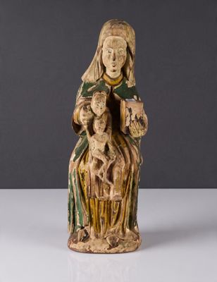 une vieille statue représentant une femme tenant un bébé et un chien dans ses bras