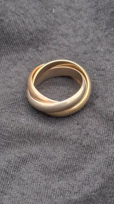 un gros plan d'une bague en or posée sur un tissu gris