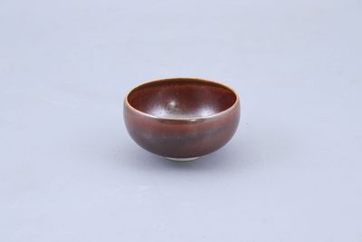 un petit bol marron posé sur une table blanche