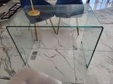 a glass table with two blue chairs in the middle of the room