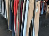 clothes hanging on a rack in a clothing store next to a brick wall