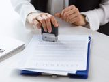someone is stamping a document with a rubber stamper on a desk